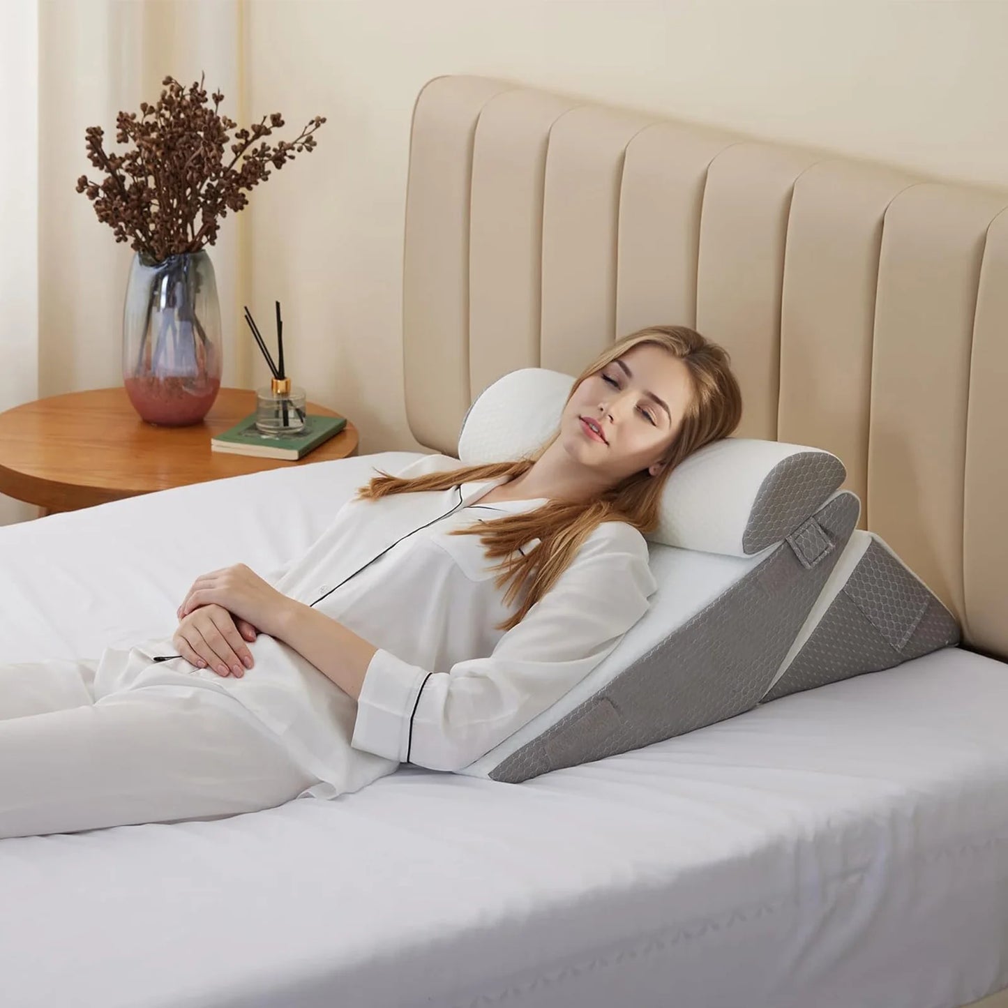 Woman lying on a bed with a wedge pillow for comfort, in a bedroom setting.