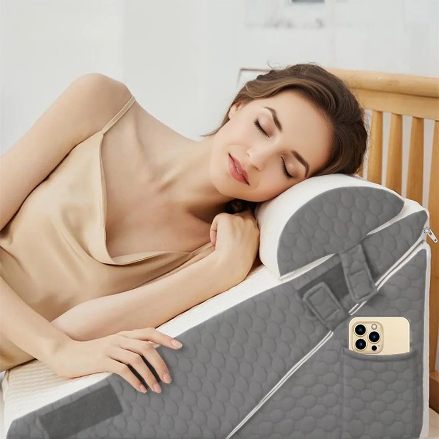 Woman lying on a bed with a gray wedge-shaped pillow and a phone in a pocket.