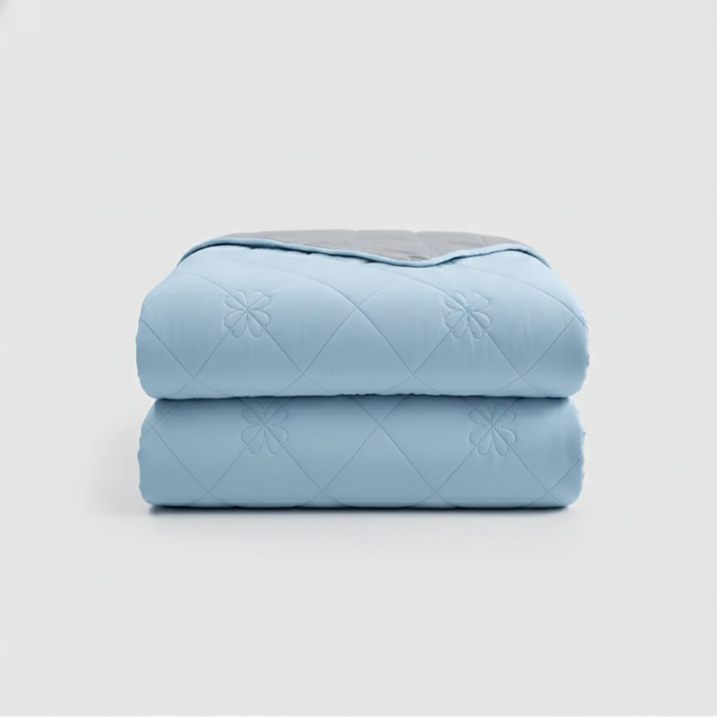 Two folded blue quilts stacked on a light gray background