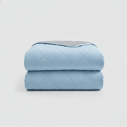 Two folded blue quilts stacked on a light gray background