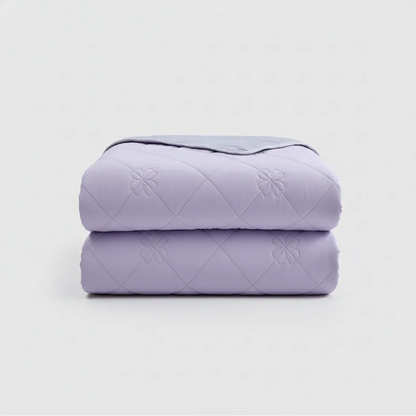 Folded purple quilt on a light gray background