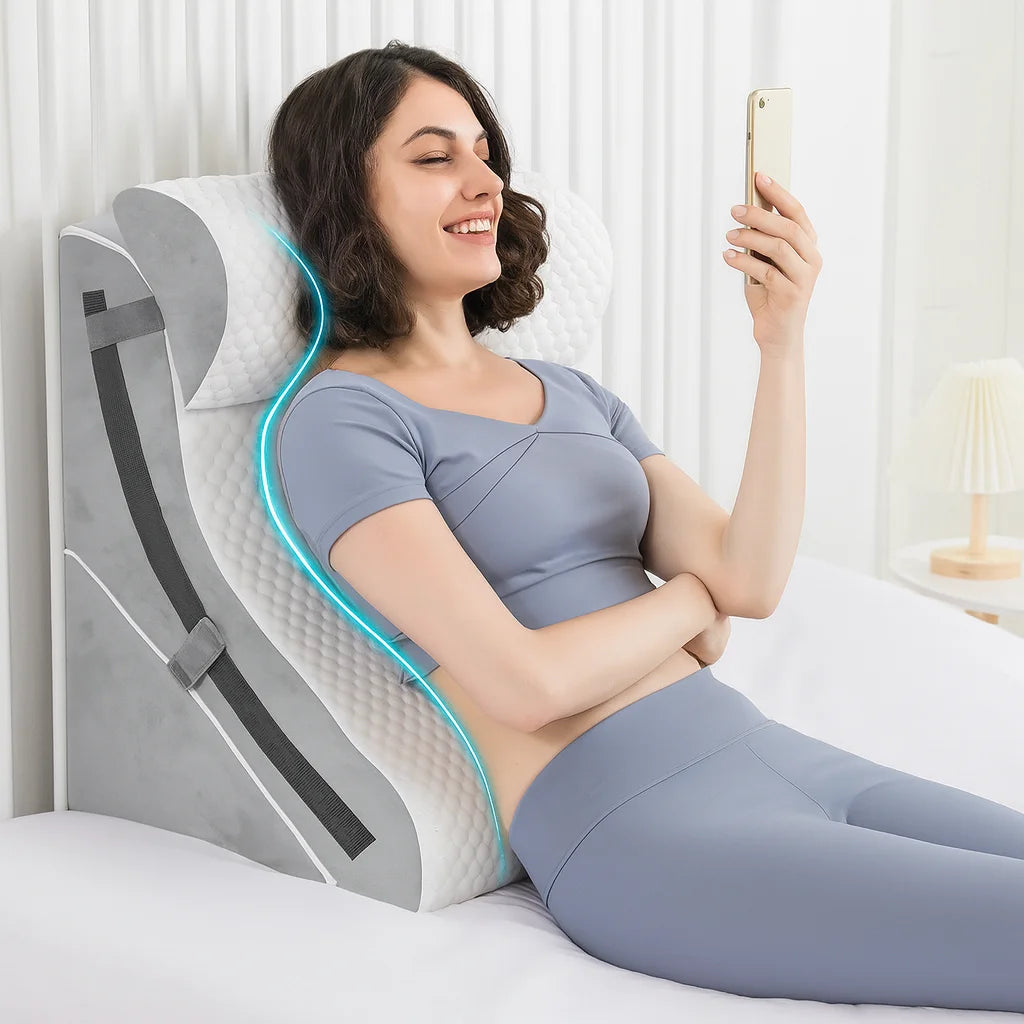 Woman using a back support pillow in bed while holding a phone.