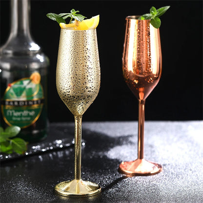 Two sparkling cocktails in gold and rose gold flutes with a bottle in the background.