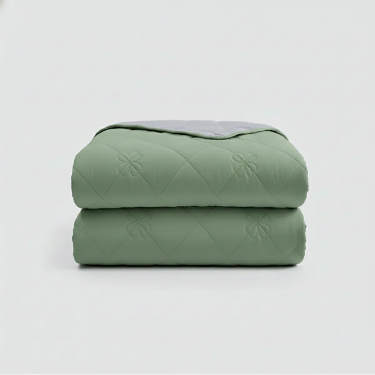 Stack of green quilted blankets on a light gray background