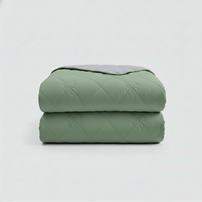 Stack of green quilted blankets on a light gray background