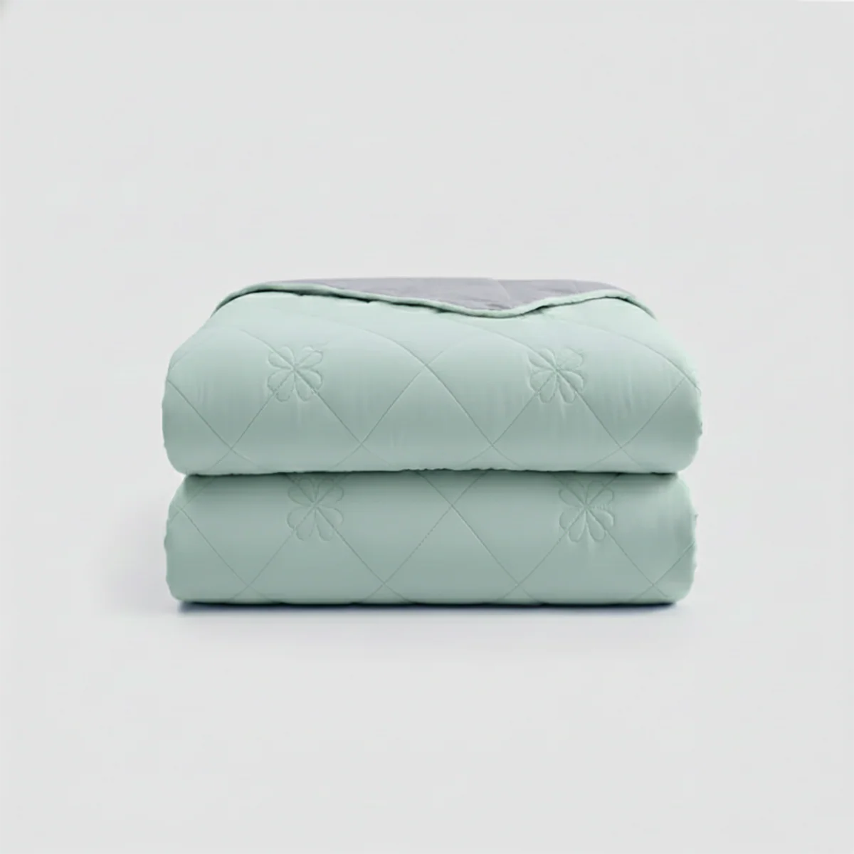 Stack of light green quilted blankets on a white background