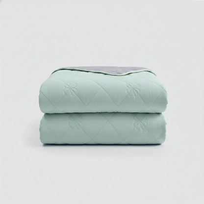 Stack of light green quilted blankets on a white background
